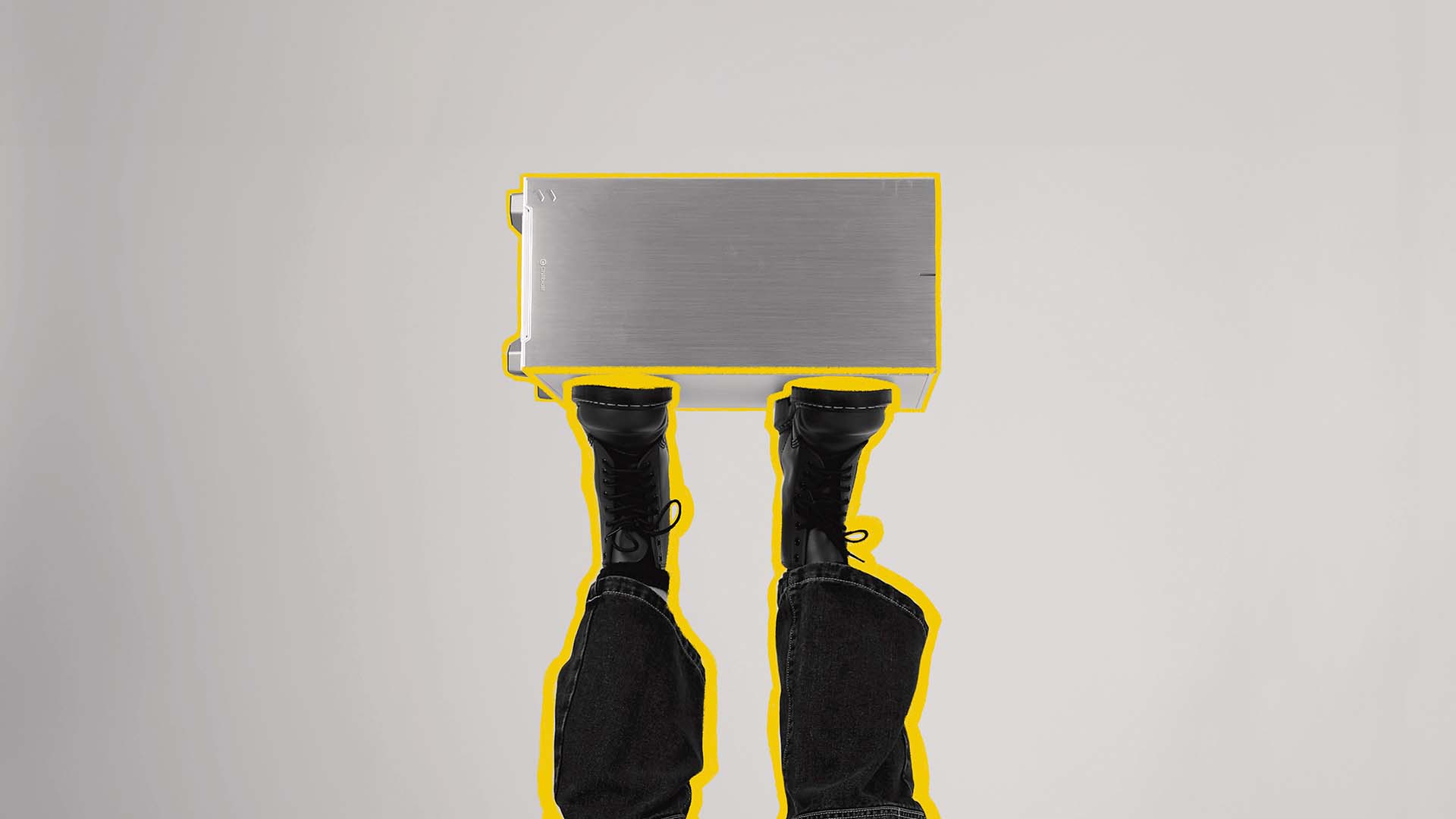 Overhead view of a Chillblast Spark workstation with yellow highlights beside a creator’s boots.