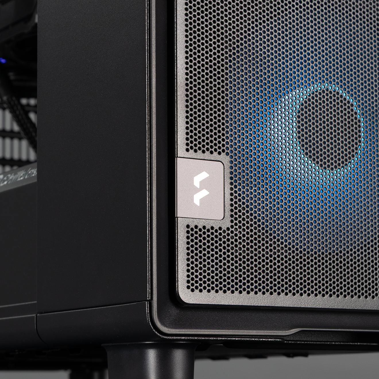 The front of the PC, showing the Fractal logo and one front fan lit up in a blue and purple gradient
