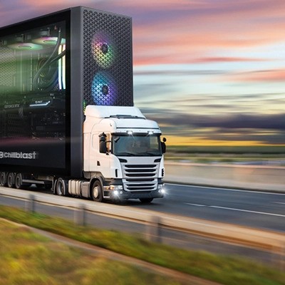 Creative depiction of a Chillblast PC as the trailer of a speeding delivery truck on a highway, with vibrant RGB-lit fans visible in the front panel, set against a scenic sunset background, symbolizing fast and efficient delivery.