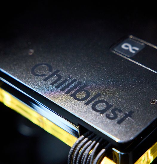 Close-up of the custom graphics card inside the Chillblast Obsidian PC, featuring the Chillblast logo engraved on a sleek black surface, illuminated by subtle yellow lighting and showcasing premium build quality.