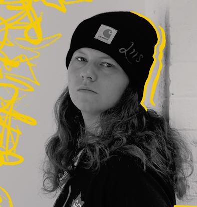 Portrait of a video editor wearing a black beanie and casual attire, set against a background with yellow graffiti-style accents, representing the creative professionals who use the Chillblast Spark Creator PC range.