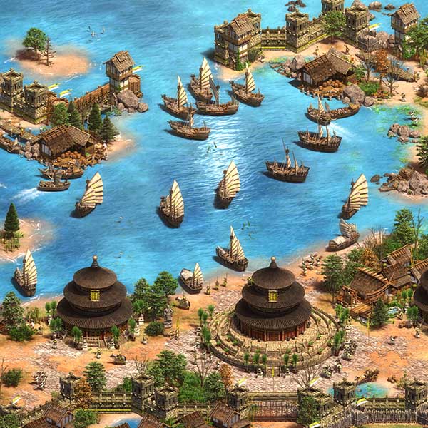 Screenshot from Age of Empires II: Definitive Edition showing a coastal Asian-style civilization with traditional architecture, fishing boats, and naval ships in a large harbour.